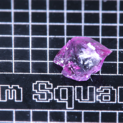 A synthetic ruby crystal on a black grid background