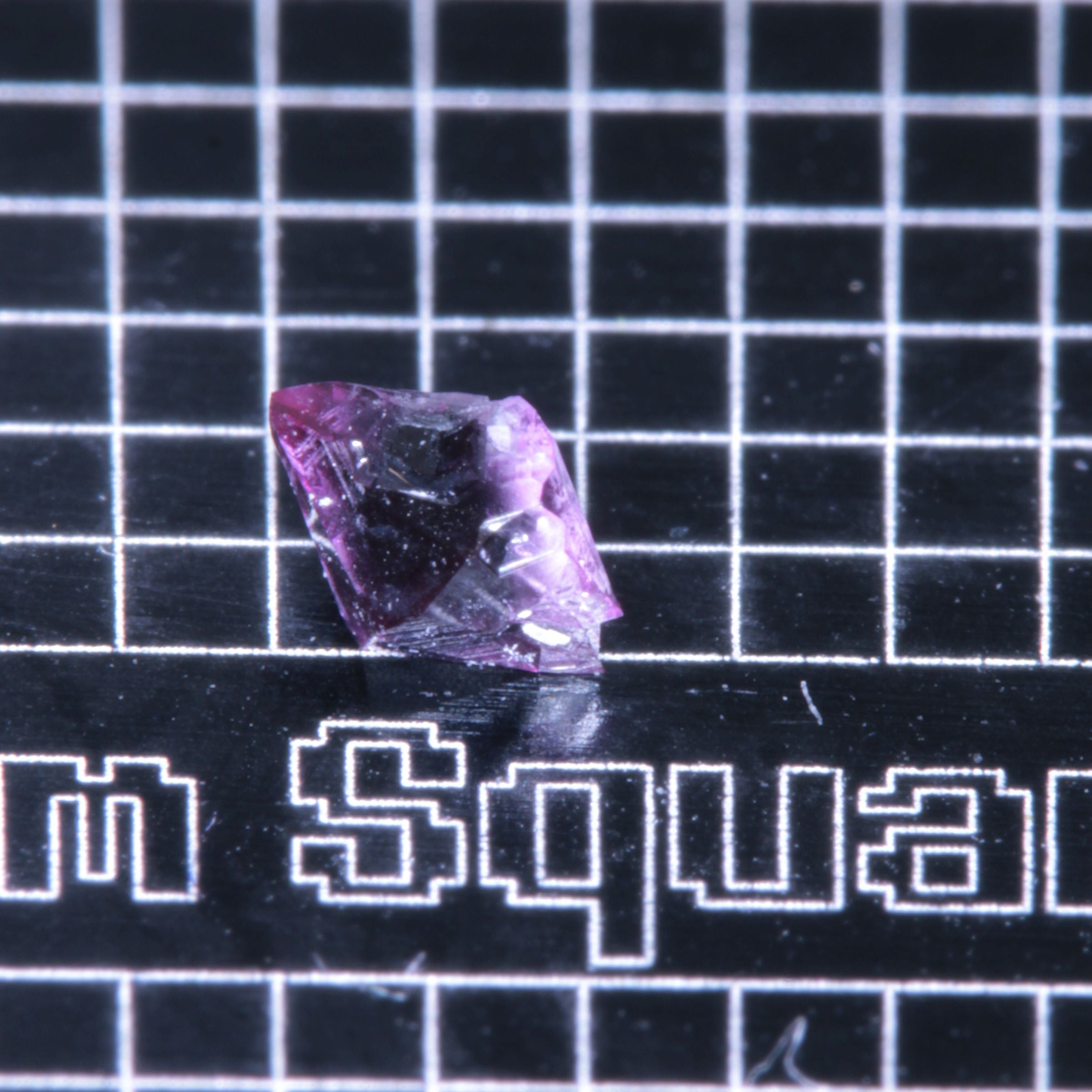 A synthetic ruby crystal on a black grid background