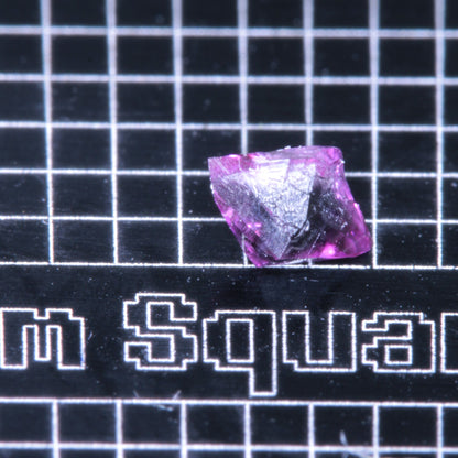 A synthetic ruby crystal on a black grid background