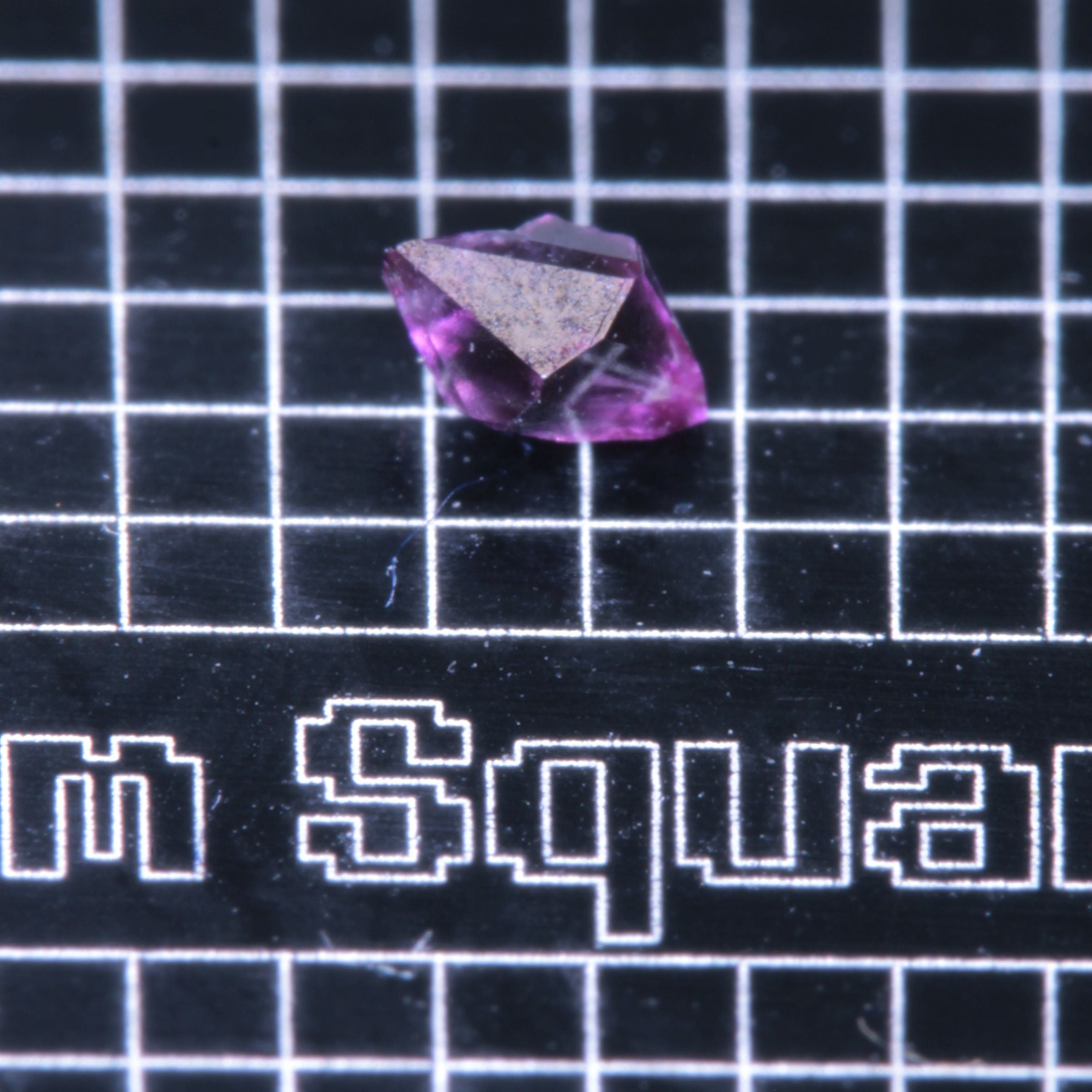 A synthetic ruby crystal on a black grid background