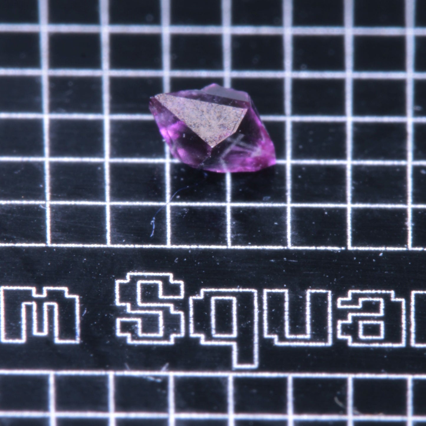 A synthetic ruby crystal on a black grid background