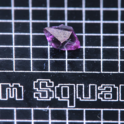 A synthetic ruby crystal on a black grid background