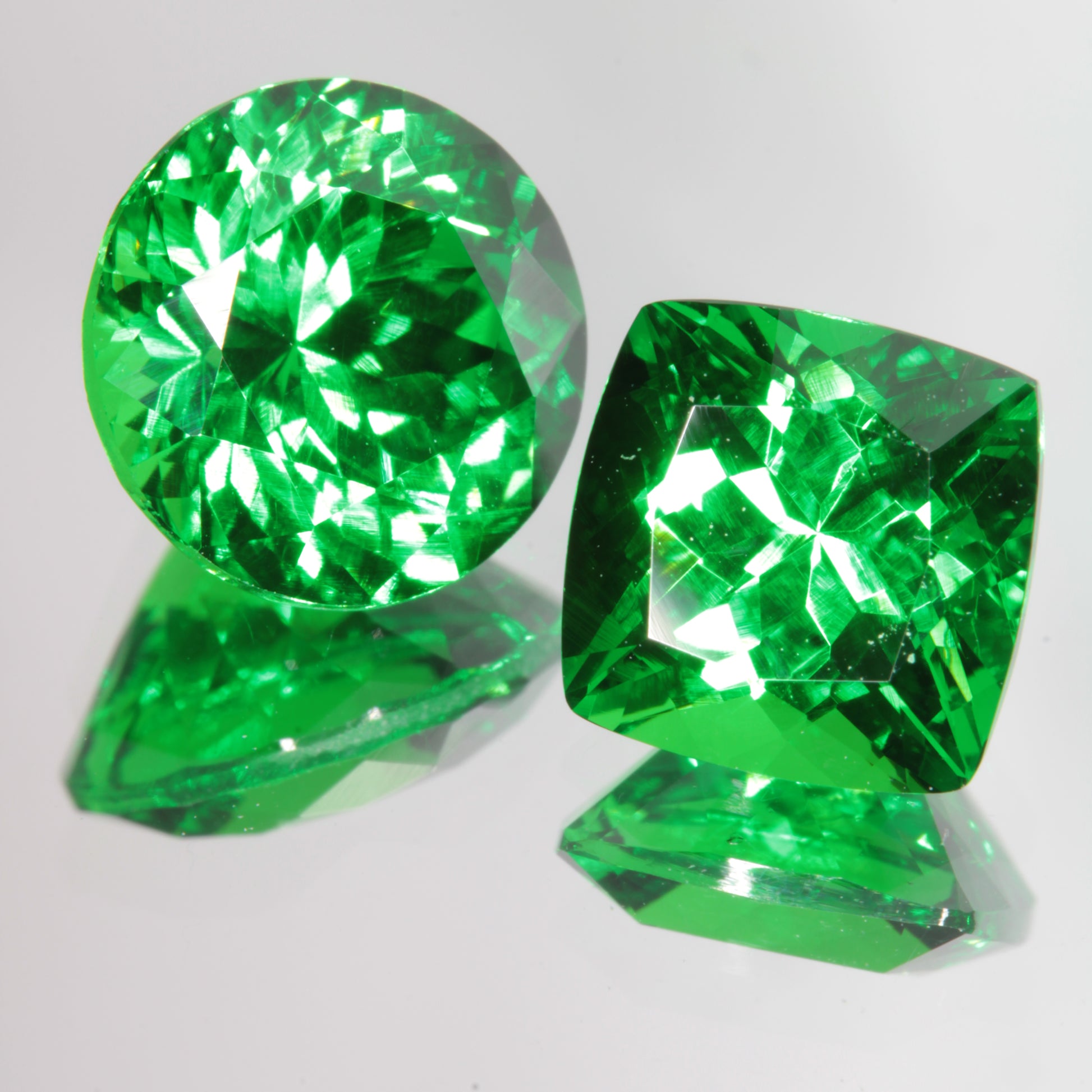 Green Labmade CTH:YAG Gems (Chromium, Thulium, Holmium Yttrium Aluminum Garnet), Round Cut on the left, Cushion Cut on the right
