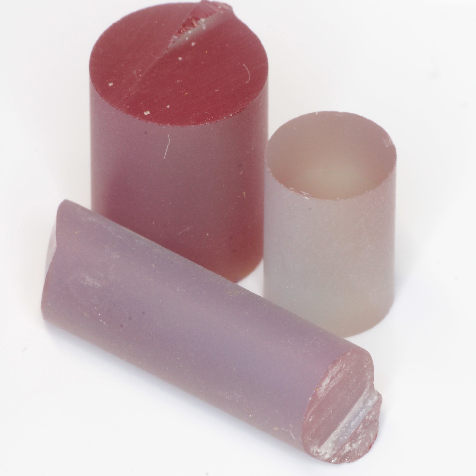 Three laser alexandrite rods of different diameters on a white background, showing their red, green and blue hues