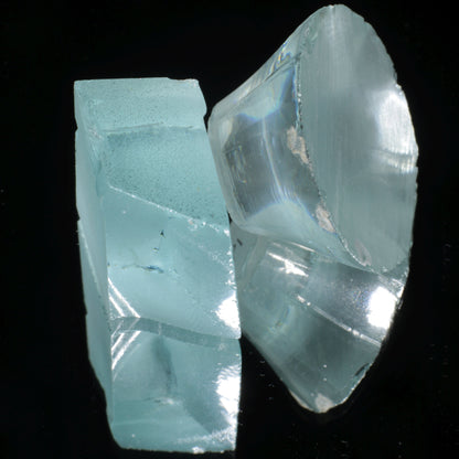 Two pieces of light blue Yb:YAG crystal on a black background