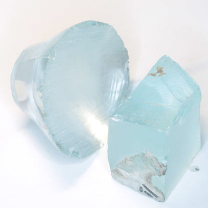 Two light blue pieces of Yb:YAG crystal on a white background