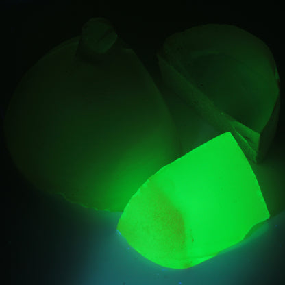 Three pieces of flame fusion green spinel under 365nm UV showing the green glow