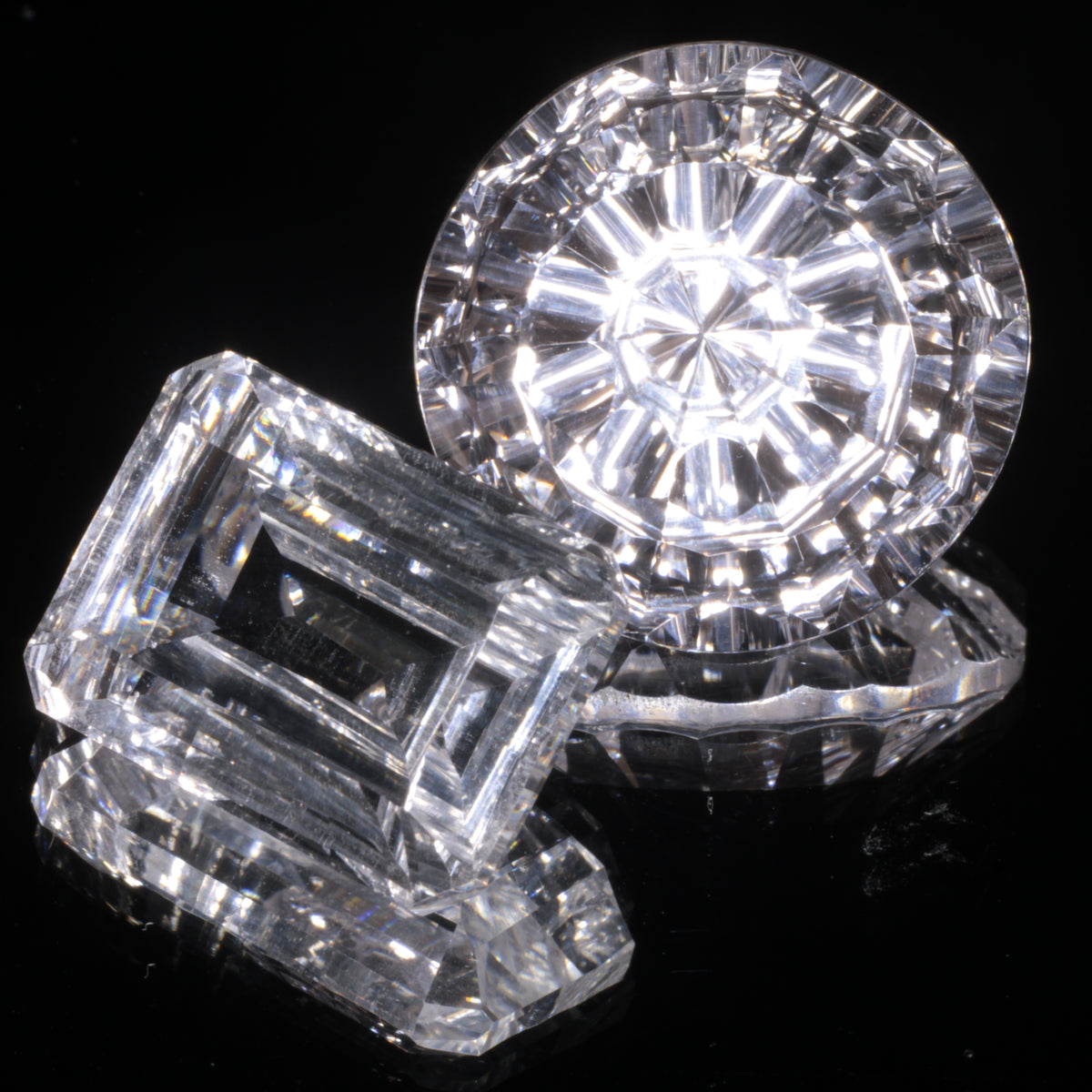 Two Faceted White Optical Sapphires on a Mirrored Background