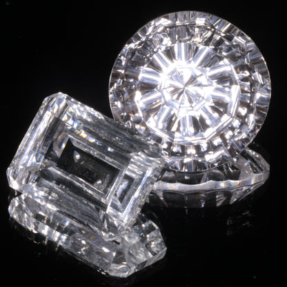 Two Faceted White Optical Sapphires on a Mirrored Background
