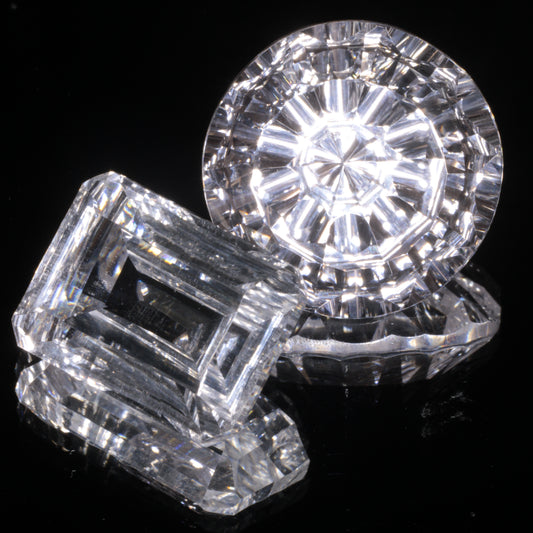 Two Faceted White Optical Sapphires on a Mirrored Background
