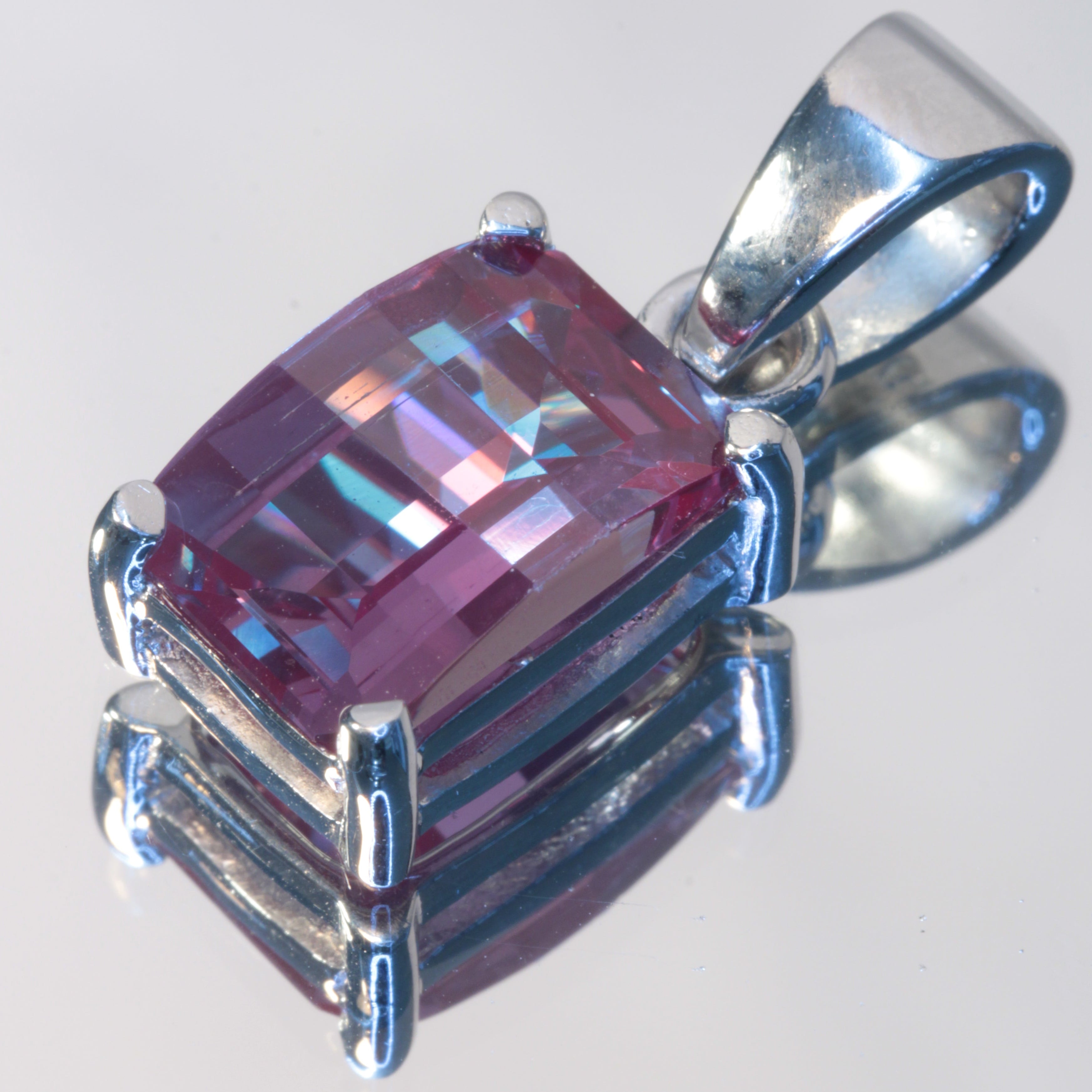 A pixel-cut lab alexandrite gemstone in a sterling silver dangle pendant, on a white background