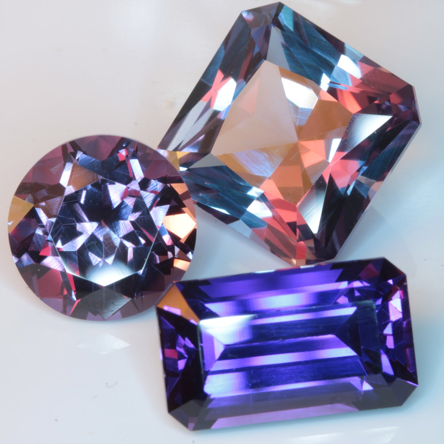 Three Color Change Purple Sapphires shown under mixed lighting, demonstrating the different colors produced