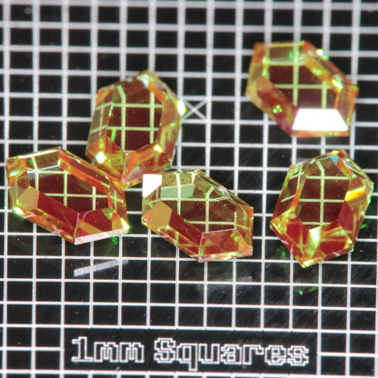 RetroHex faceted Christmas Garnets on a 1 mm grid for scale, Red and Green Cr+3:YAG gemstones