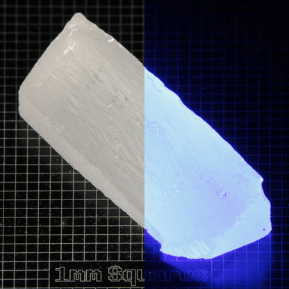 Long Wedge of LSO Gem Rough on a dark background, split between normal light (left) and UV (right) to show blue fluorescent glow.