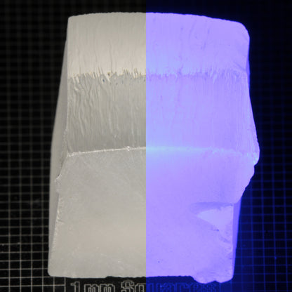 Block of LSO Gem Rough on a dark background, split between normal light (left) and UV (right) to show blue fluorescent glow.