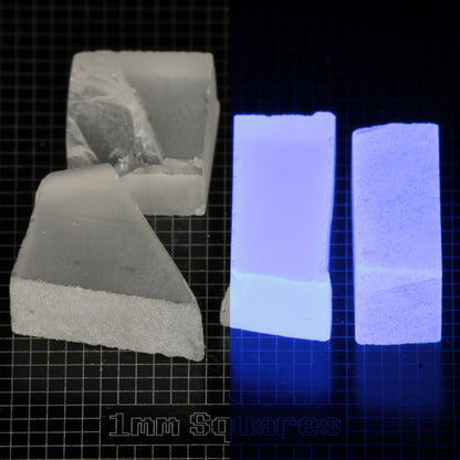 Several pieces of of LSO Gem Rough on a dark background, split between normal light (left) and UV (right) to show blue fluorescent glow.