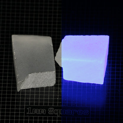 Several pieces of of LSO Gem Rough on a dark background, split between normal light (left) and UV (right) to show blue fluorescent glow.