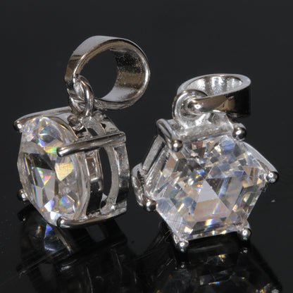 Two faceted TGG pendants set in sterling silver on a black background, showing their strong green fluorescene under UV