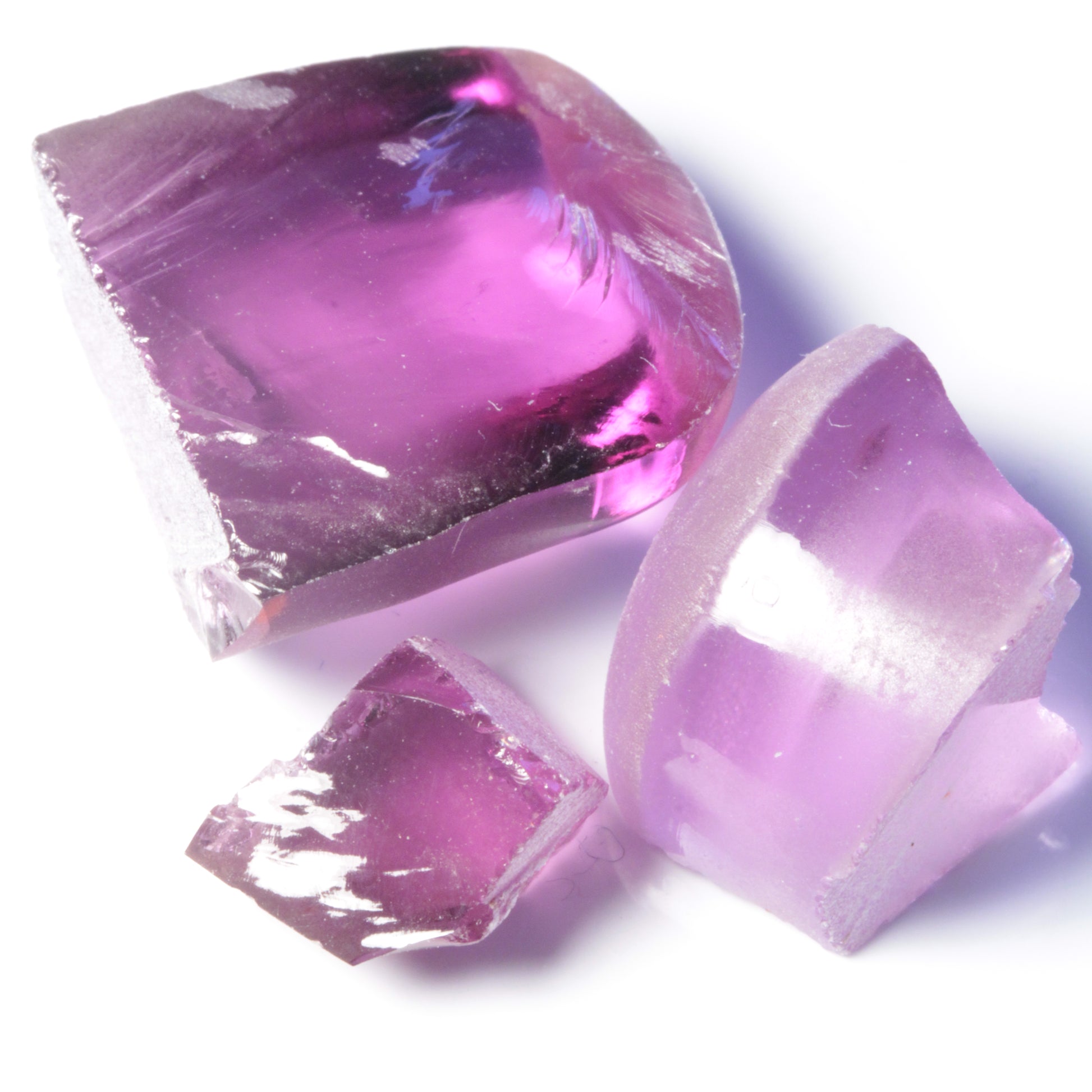 Three pieces of flame fusion sapphire under warm LED lighting showing redder purple colors.