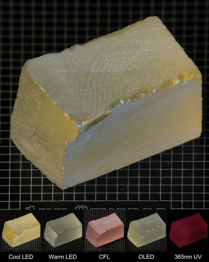 Darker Block of Ho:YAG Gem Rough, showing color changes from yellow to pink under different lighting conditions.