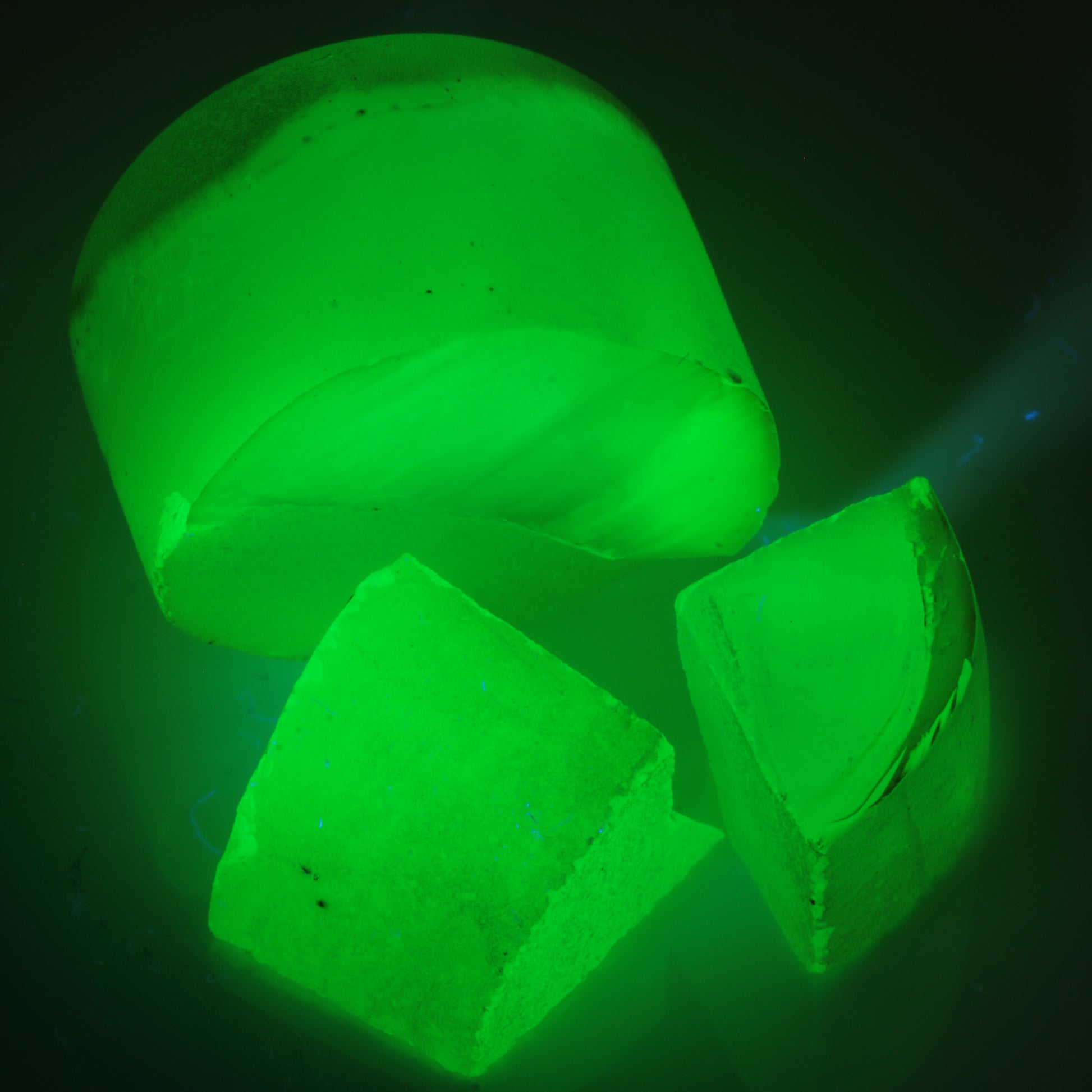 Yellow flame fusion spinel purely under 365nm UV, showing the green glow