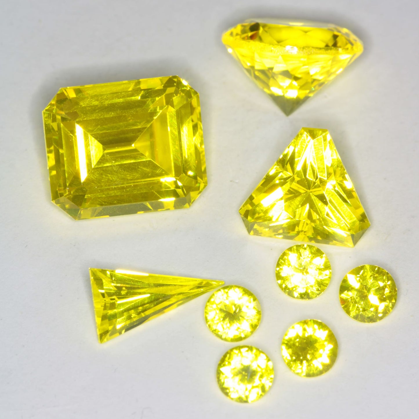 Several Faceted Cerium GAGG gems on a white background